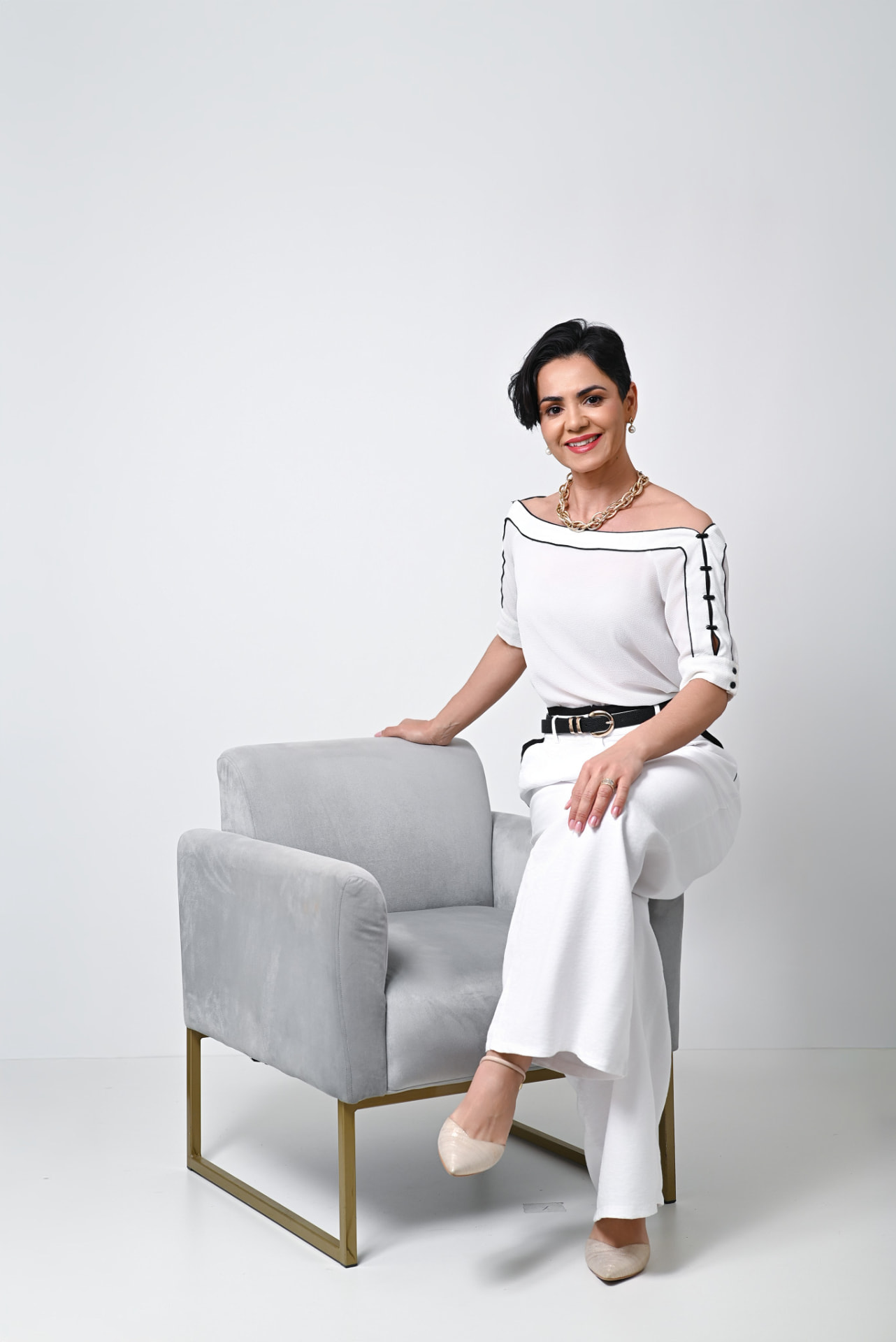 Fabi Souza sorrindo, sentada em uma poltrona